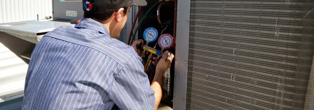 HVAC technician servicing a condenser unit in Belle Haven
